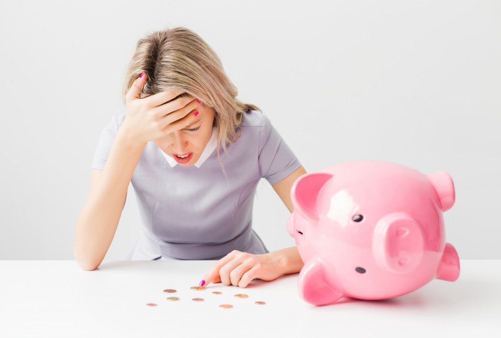 woman stressed out while counting coins from a piggybank