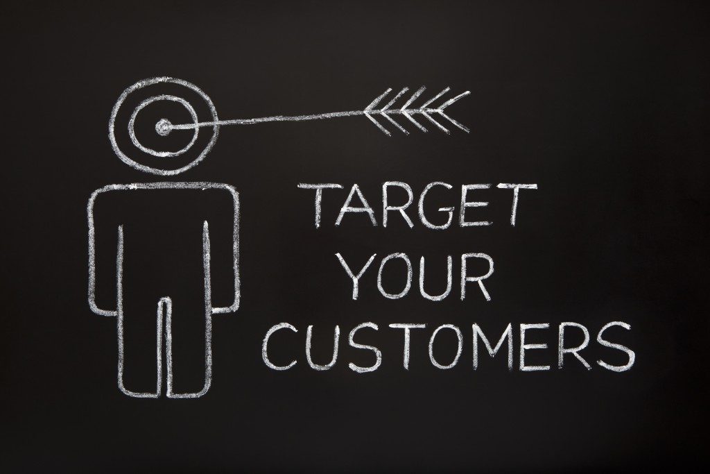 'Target your customers' concept made with white chalk on a blackboard.
