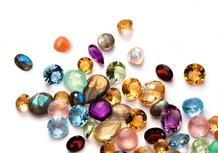 Collection of many different natural gemstones on the white background: amethyst, lapis lazuli, rose quartz, citrine, ruby, amazonite, moonstone, labradorite, chalcedony, blue topaz and many more.