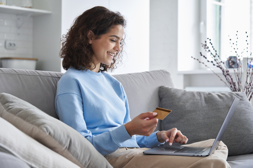 a woman holding a credit card while using a laptop