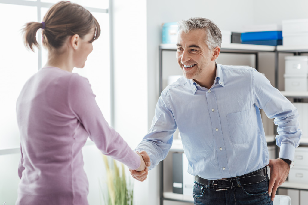 A male employer shaking hands with a female employee