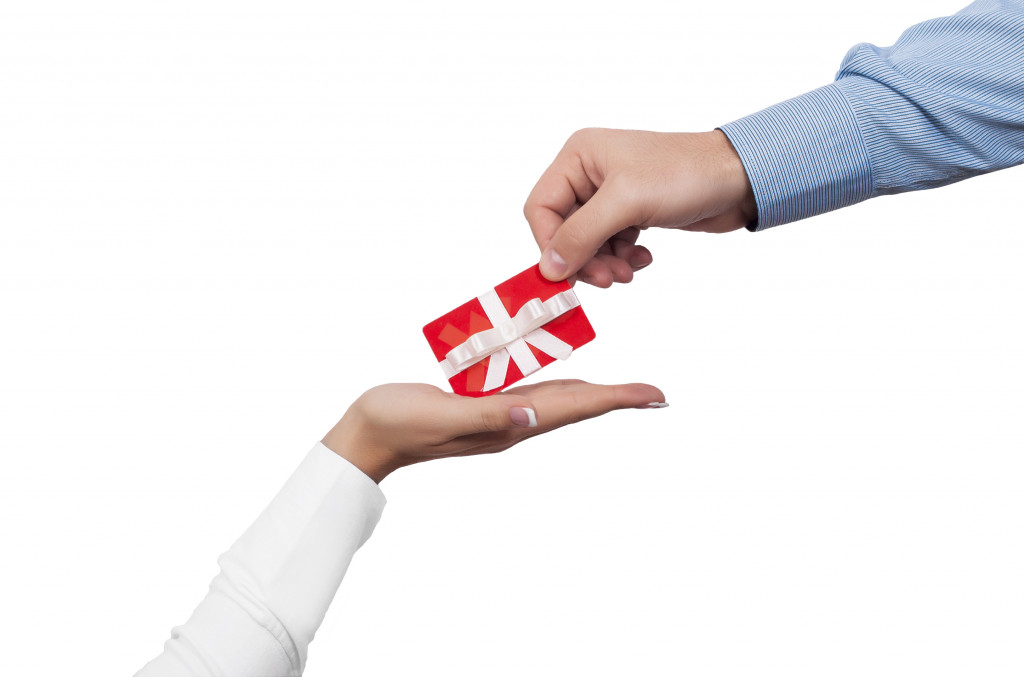 a person giving a red gift card to a woman's hand