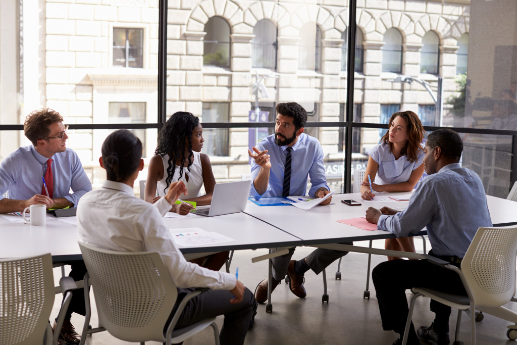 a male businessman having a discussion in the middle of employees in a meeting room