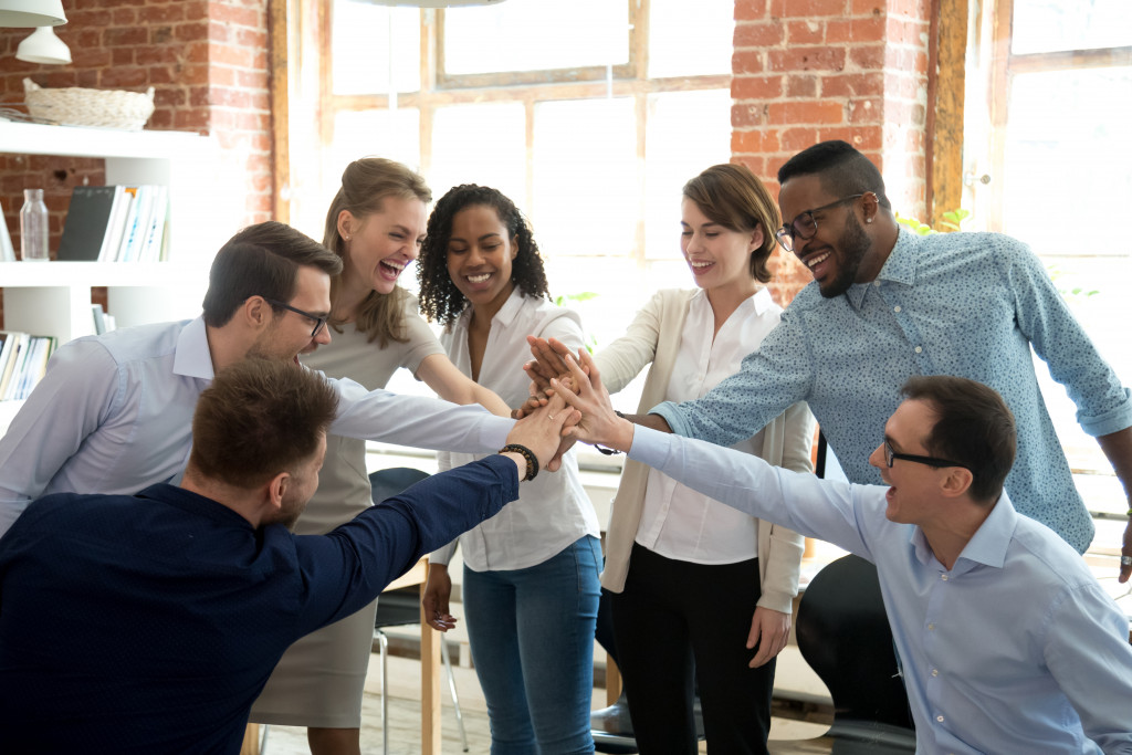 multiracial employees doing high five concept of engaged team