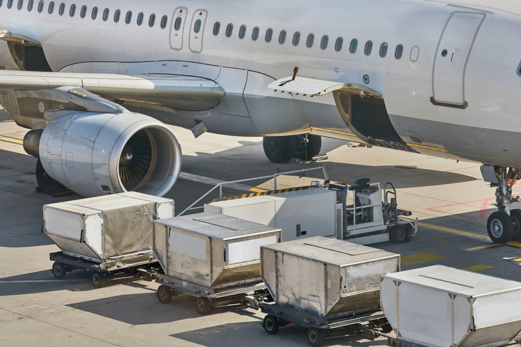 Several cargo containers lined beside an airplane