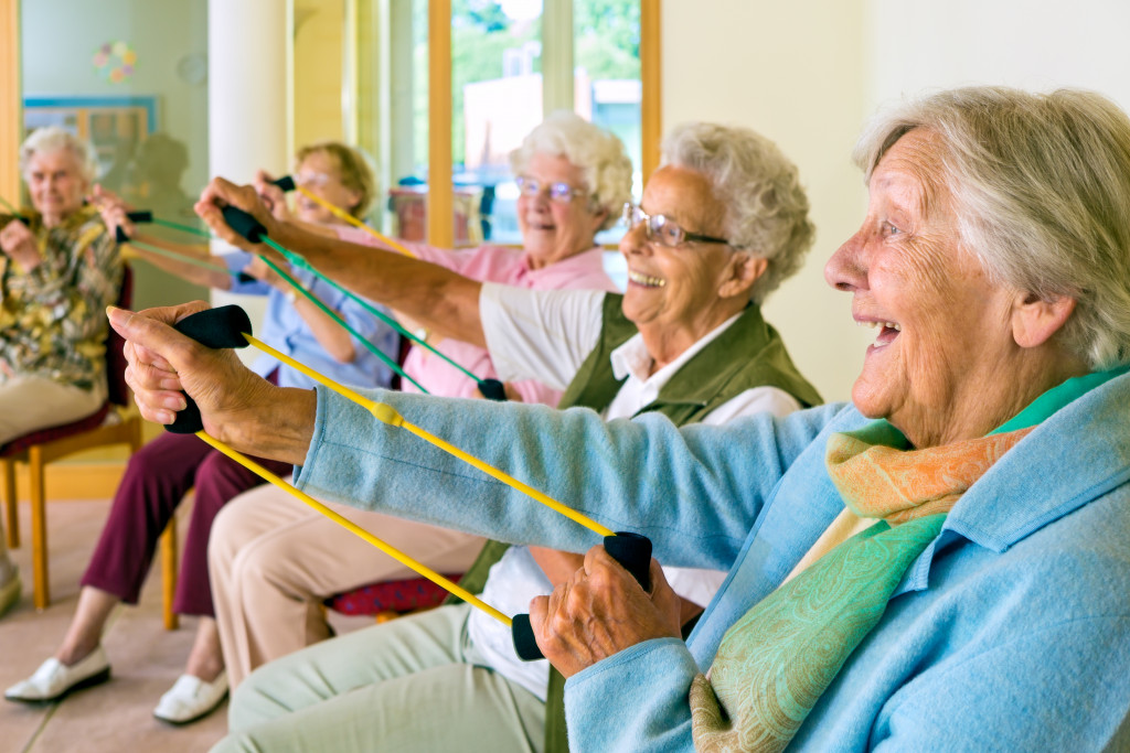 Happy seniors doing band exercise while seated