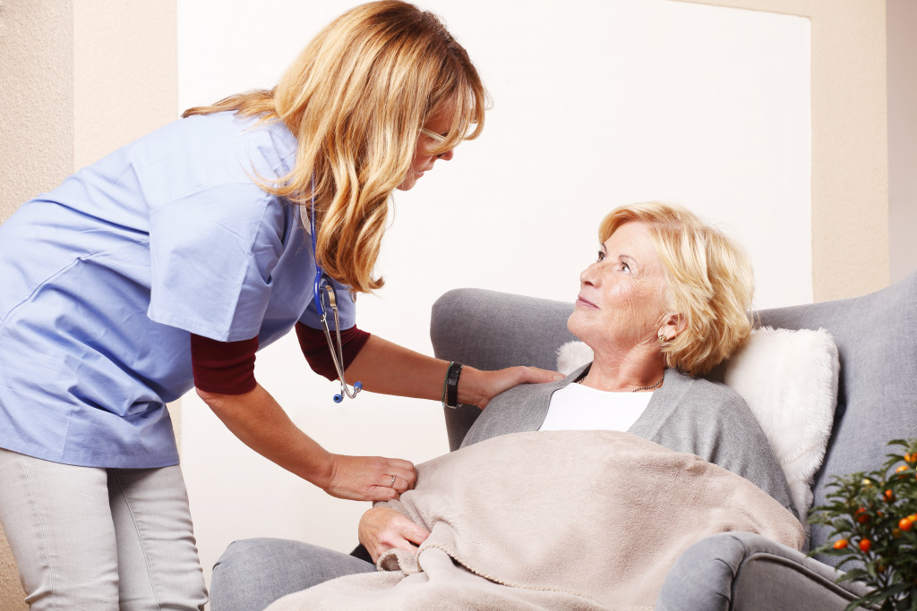 A nurse taking care of a senior lady while sitting comfortably