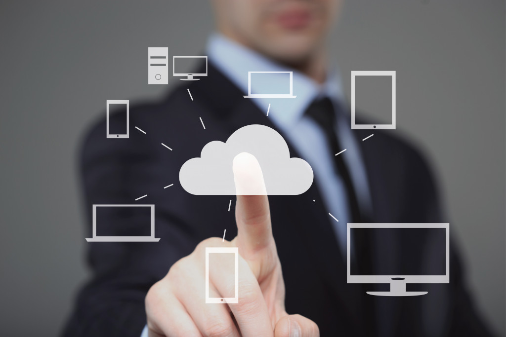 A businessman pressing a cloud button connected to several gadgets