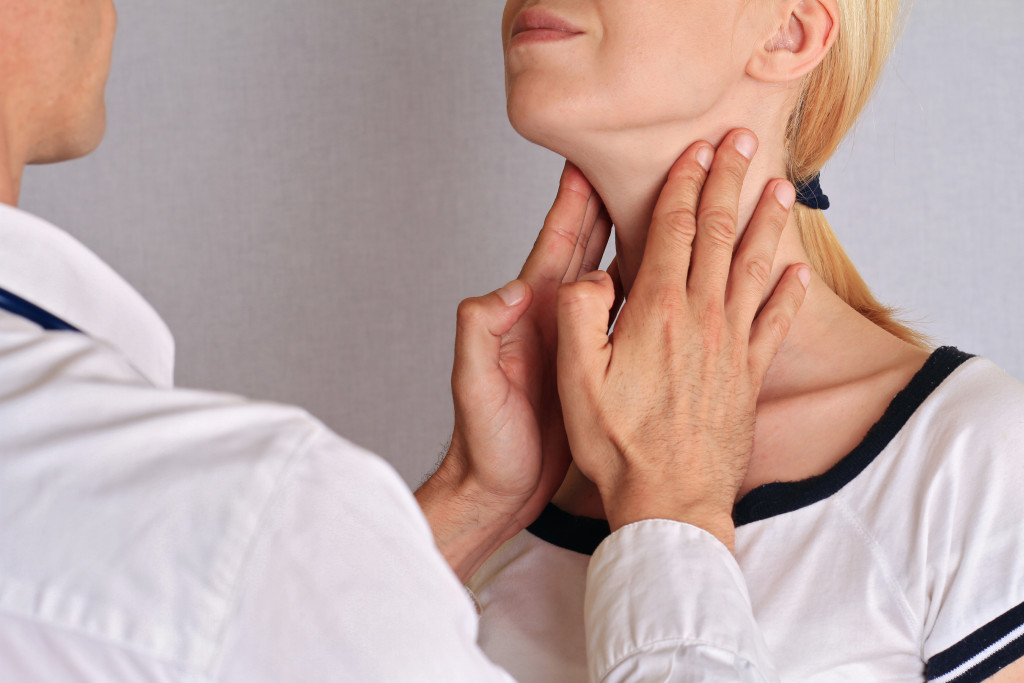 A woman getting her thyroids checked by a doctor
