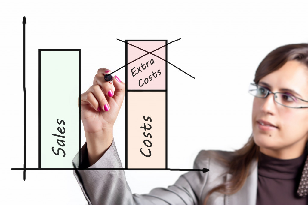 woman crossing out extra costs in budget graph by minimizing costs