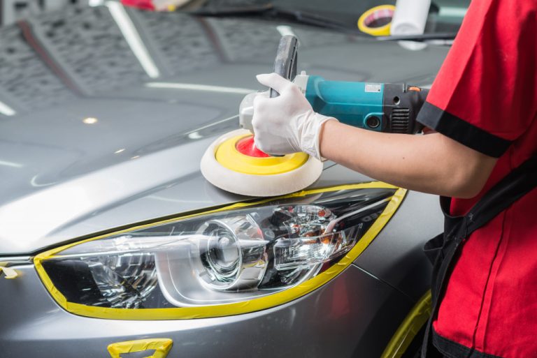 Worker polishing a car's headlights