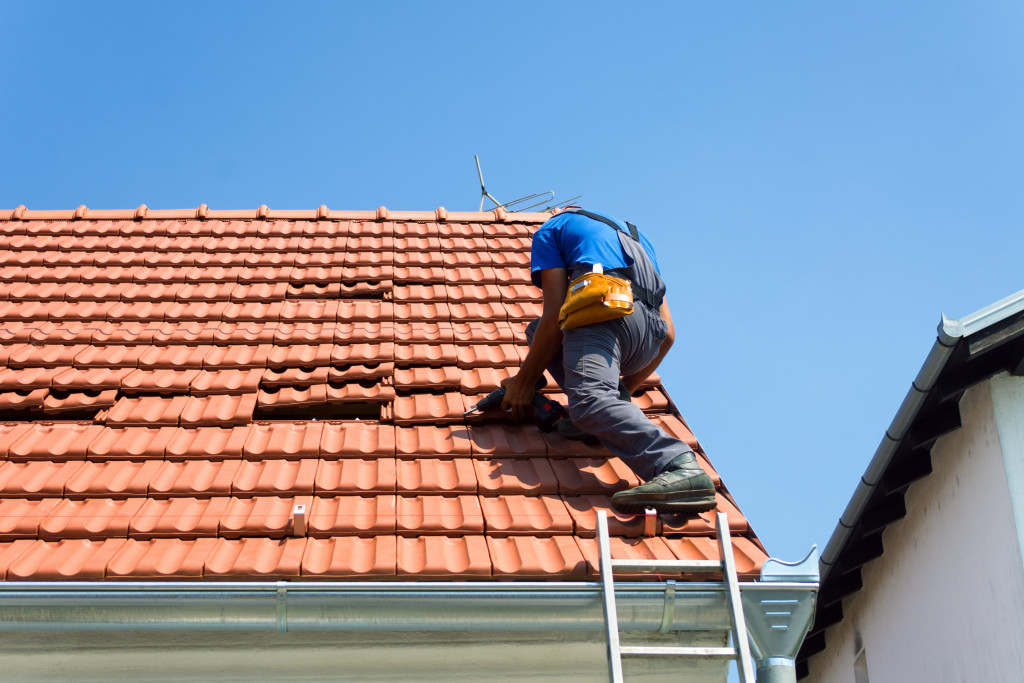 male roofer fixing and installing a new roof portion in daylight