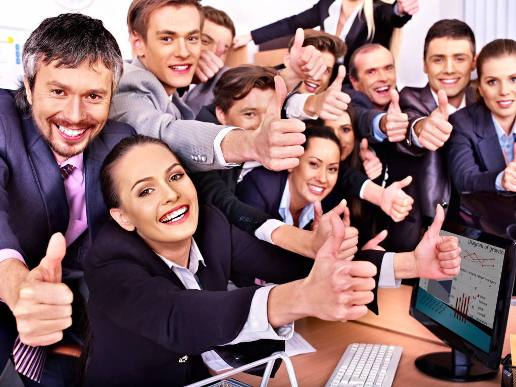 a group of people giving thumbs up in office