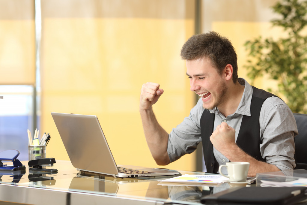person rejoicing in front of his laptop at office representing incentives