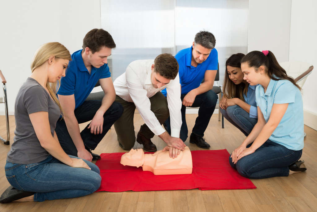 a first aid instructor doing a CPR to a mannequin in front first aid trainees