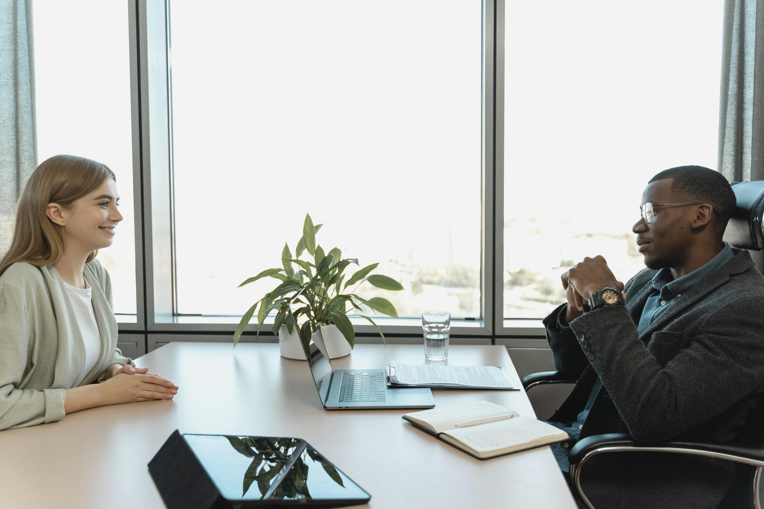 woman in a blazer being interviewed by a serious-looking HR manager in a suit